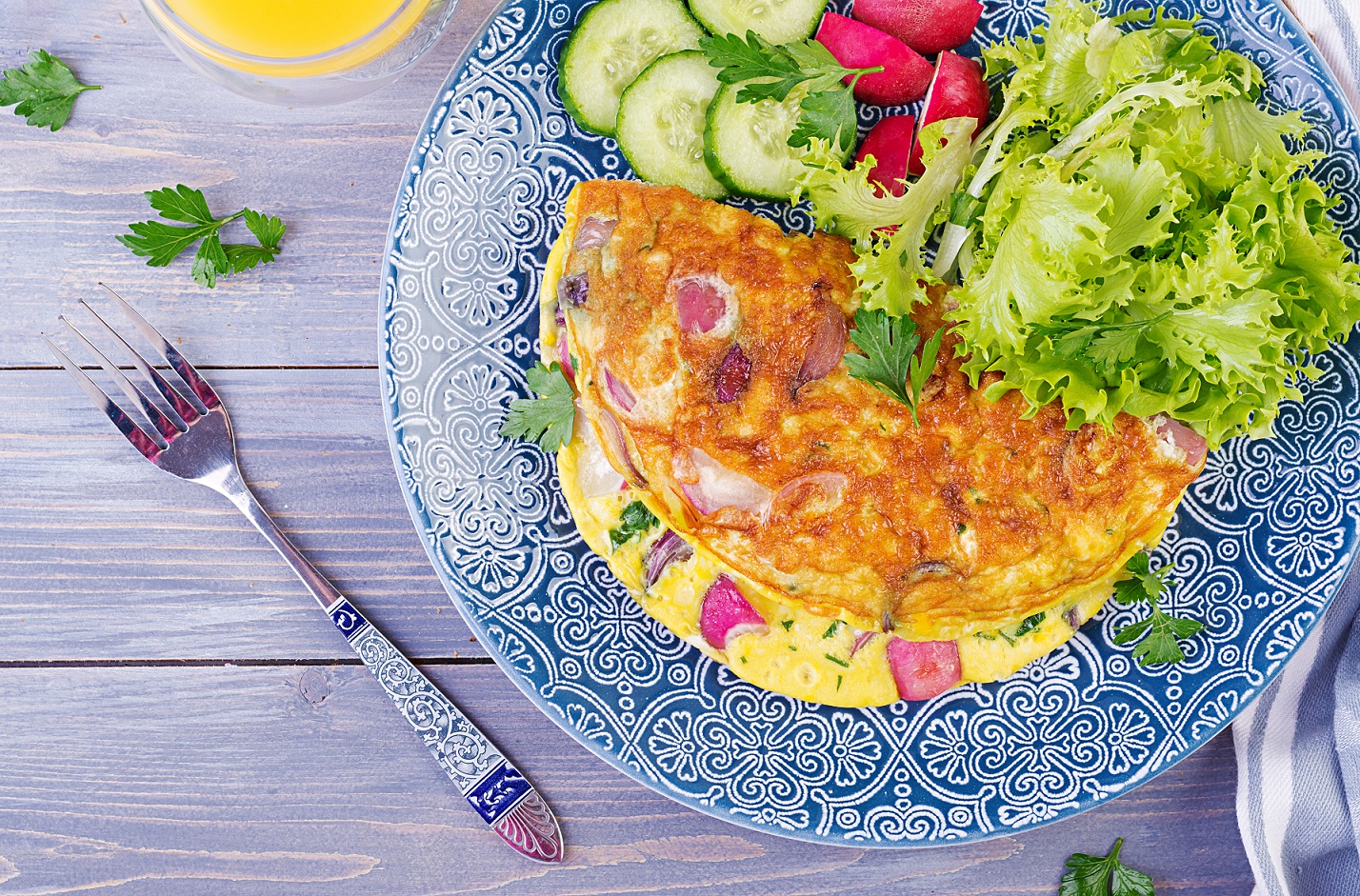 Breakfast. Omelette with radish, red onion and fresh salad on blue plate.  Frittata - italian omelet. Top view